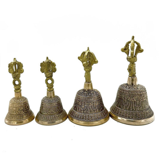 Four ornate bronze bells with intricately carved surfaces stand in a row, featuring unique, decorative handles, set against a plain white background.