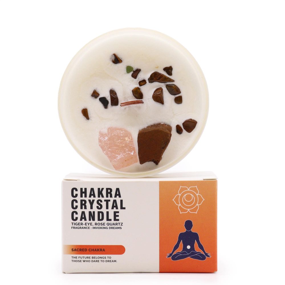 A crystal candle sits on its box. The box reads "Chakra Crystal Candle. Tiger-Eye, Rose Quartz. Fragrance: Invoking Dreams. Sacred Chakra. The Future Belongs to Those Who Dare to Dream." The candle's top is inlaid with small crystals.