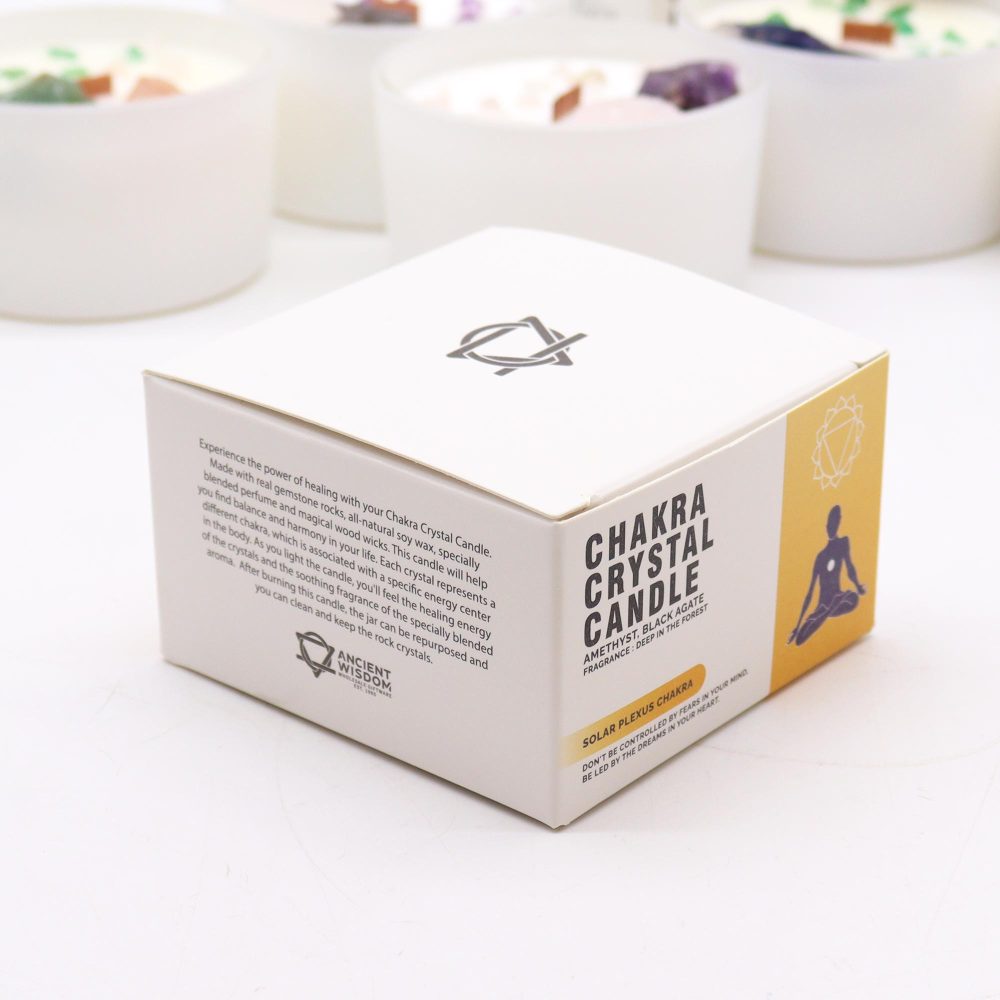 A "Chakra Crystal Candle" box sits on a white surface, next to some candles. The box reads "Chakra Crystal Candle," along with a description of the product and the phrase, "Don't be controlled by fears in your mind, be led by the dreams in your heart."