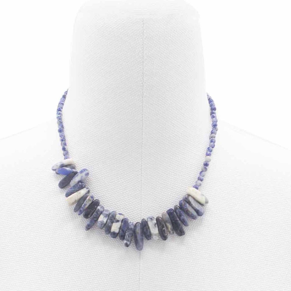 A blue and white beaded necklace, with stone accents in the center, drapes on a white mannequin against a white background.