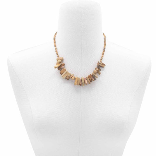 A necklace with rough, rectangular, tan-colored stones hangs on a white mannequin's neck. The necklace is rounded out by a strand of small beads.