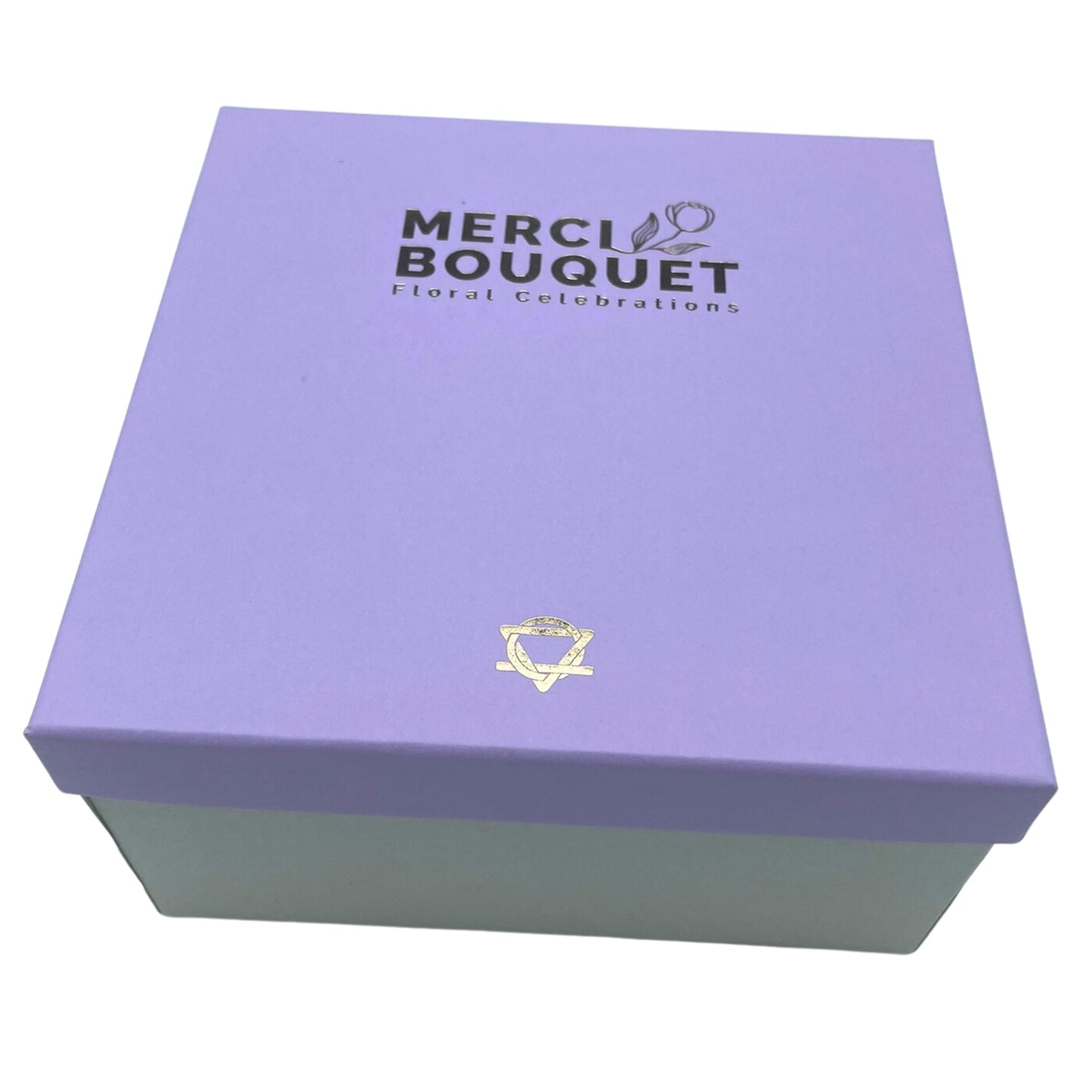 A lavender box with a silver logo sits on a white background. The logo reads "MERCI BOUQUET Floral Celebrations".