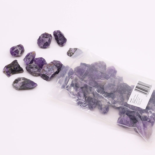Amethyst crystals spill from a plastic bag onto a white surface. The bag contains numerous additional crystals. The label reads: "Cry-02 Raw Crystals (500g) Amethyst Originated from Brazil."