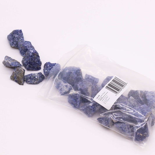Blue sodalite stones spill from a clear plastic bag onto a white surface. The bag's label reads: KCR258, Blue Sodalite Chips, 150gms, Approx. 15-25mm, 5 053338 212783.