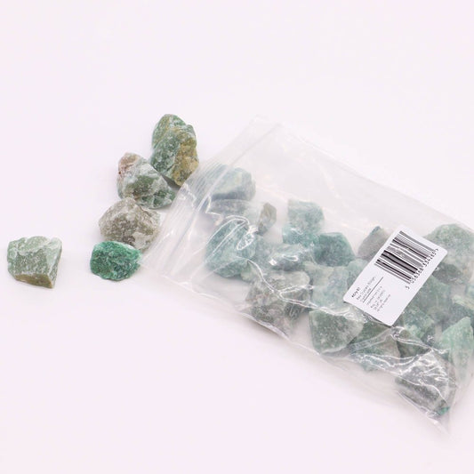 Green jade stones spilling from a plastic bag onto a white surface. The bag's label reads: "Cry-07 Crystal jade Raw Crystals (500gm Imported from C 5056368 334283".