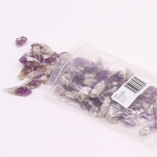 Amethyst points spill from a plastic bag onto a white surface. The bag’s label reads: RCR38 Size: 10/20(mm 300gm/1) Avg. Weight: 50-60 ct Imported from China Pkg. (LOT 214073) All materials are hand-selected. 5 056188333827.