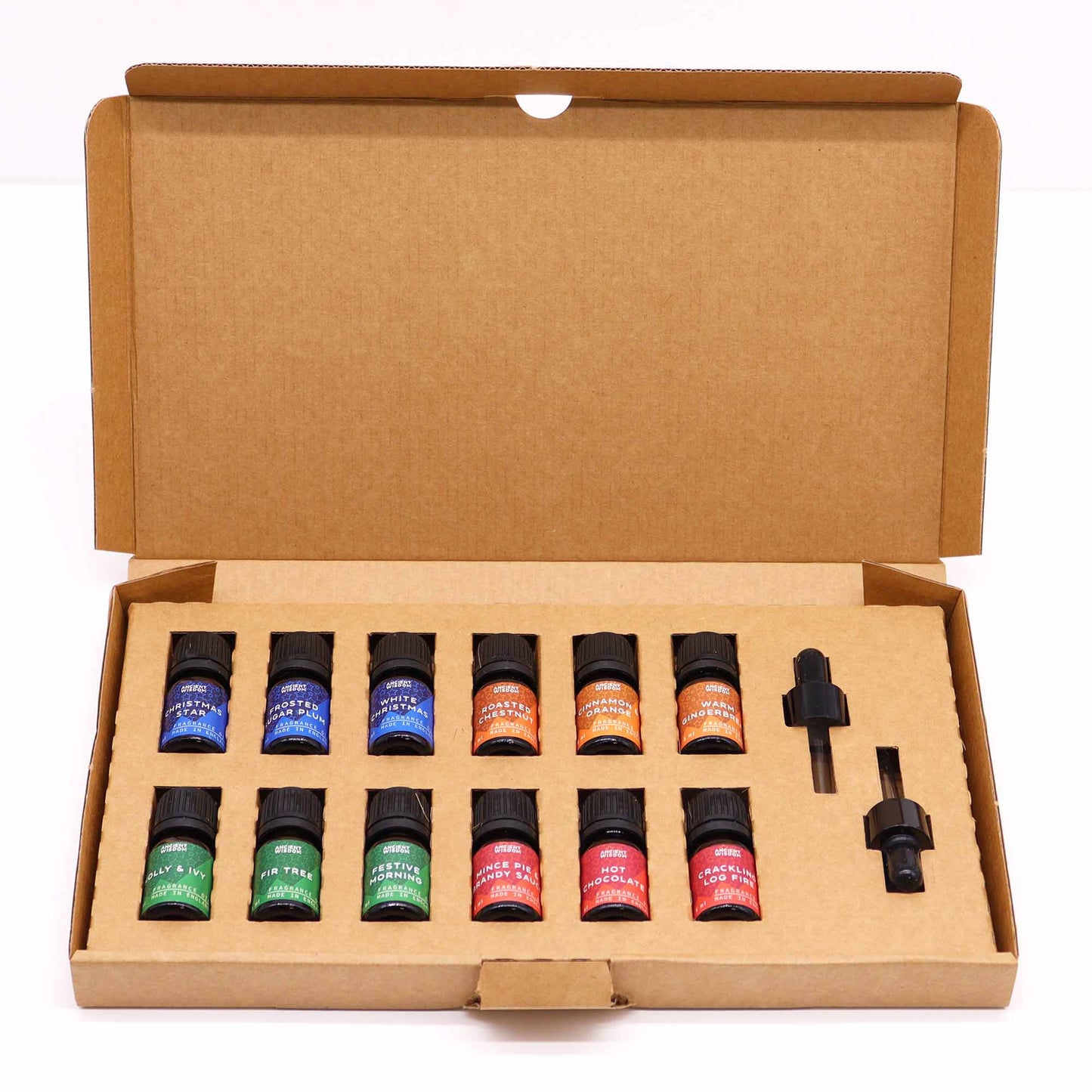 Twelve small bottles of fragrance oils are arranged in a cardboard box; two empty slots are present. A separate dropper is included.