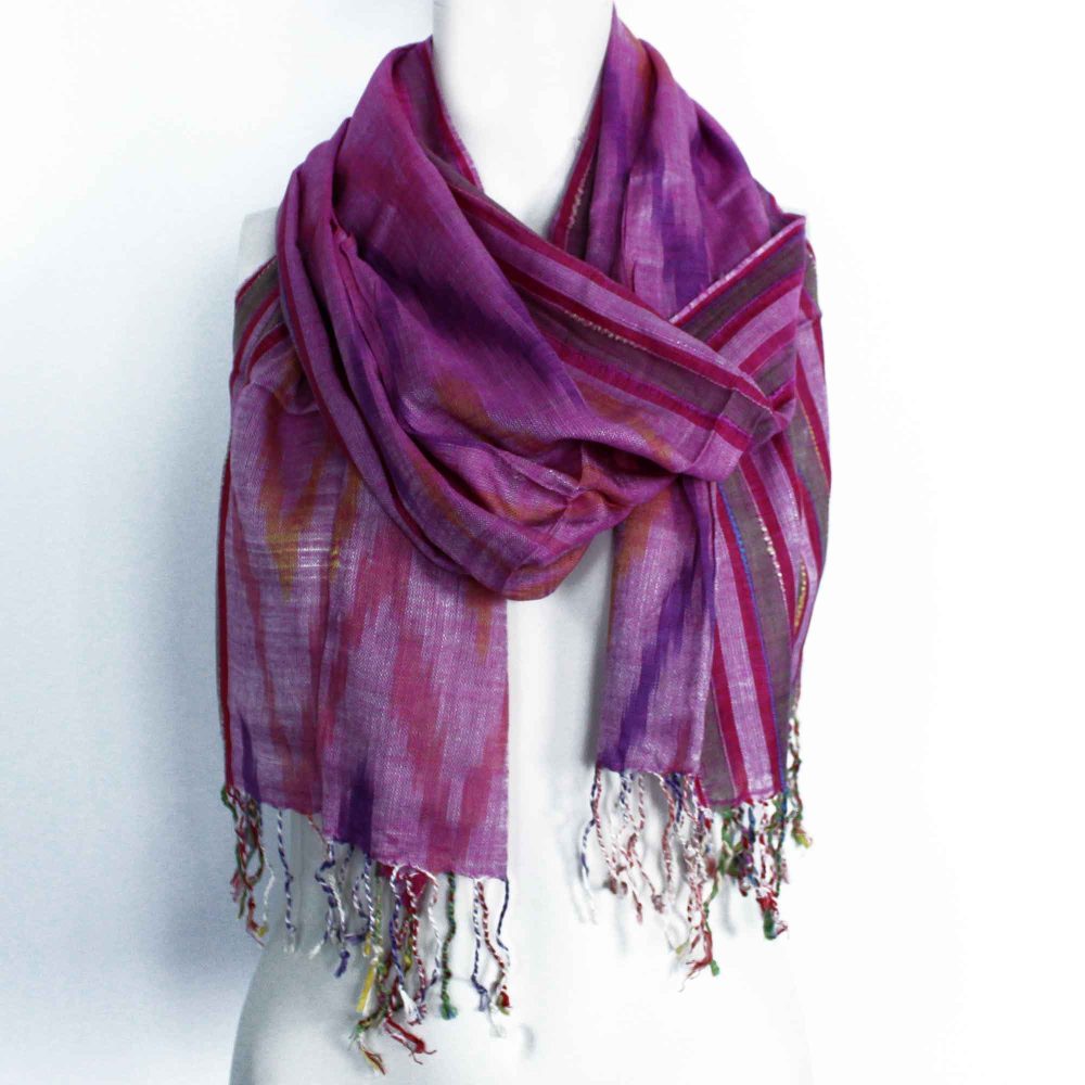A purple scarf with multicolored stripes and ikat patterns is draped around a mannequin's neck, in a white background.