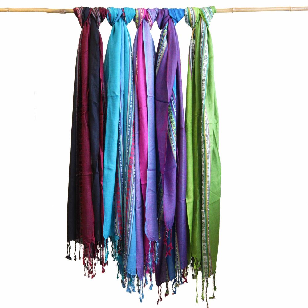 Six colorful scarves hang from a bamboo rod.  They are displayed against a white background.