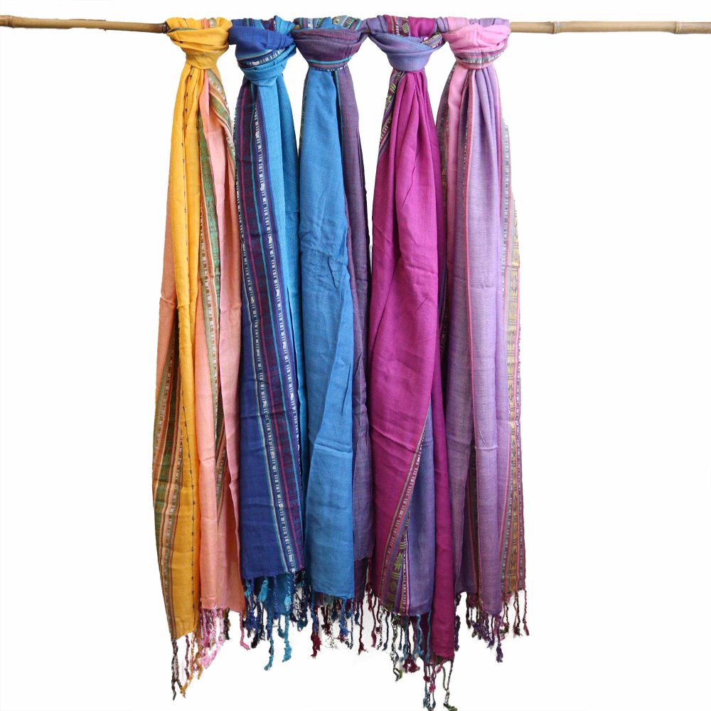 Five colorful scarves hang from a bamboo rod.  They are various shades of pink, purple, blue and orange, each with decorative trim.