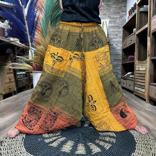 Wide-legged pants, patterned with symbolic designs in gold, green, and burnt orange, are being modeled in a rustic shop.