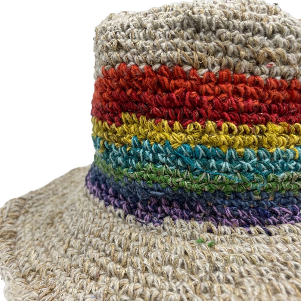 A crocheted hemp hat, featuring a rainbow band, sits against a white background.