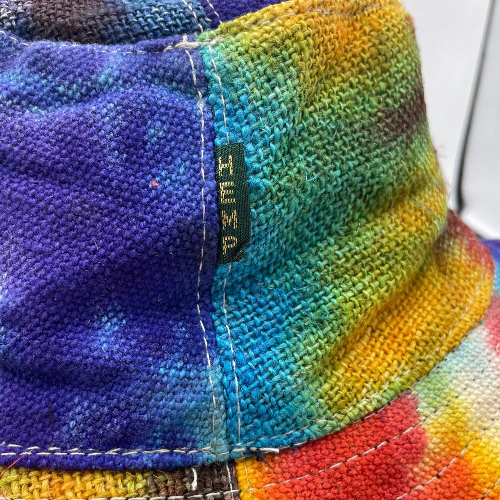 A tie-dye bucket hat rests, showing a label reading "PESH".