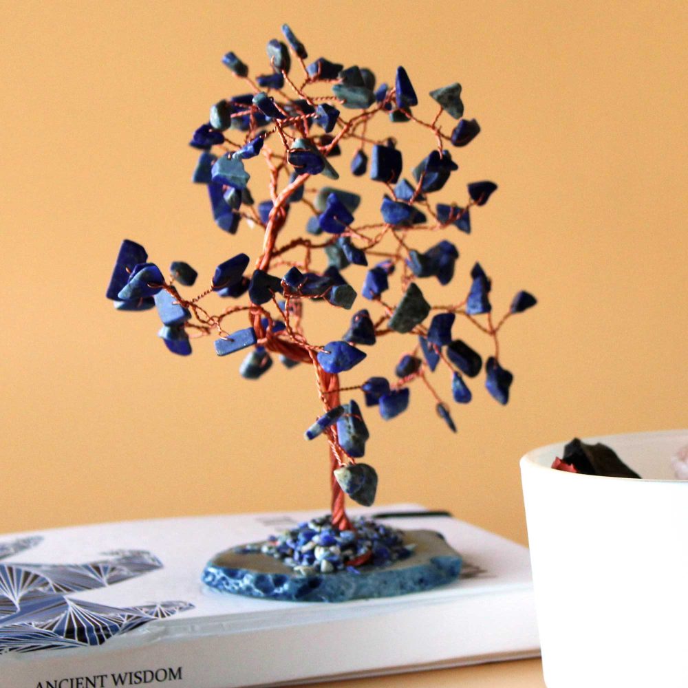 A lapis lazuli and copper wire tree sits on a book. The tree's base is also lapis lazuli. The book cover displays "ANCIENT WISDOM".