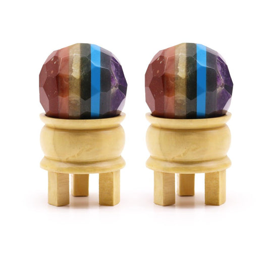 Two multicolored gemstone spheres, resting on small wooden stands, are displayed against a white background.