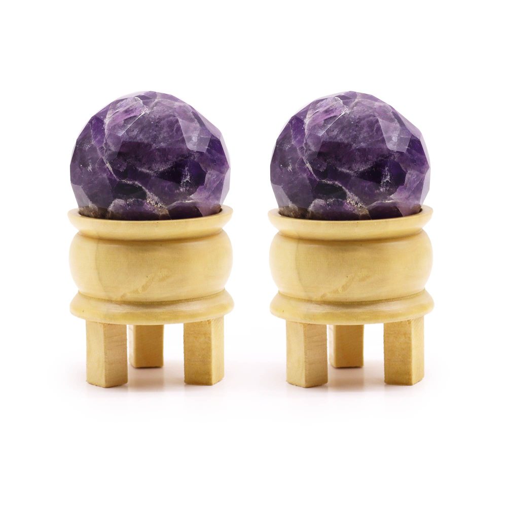 Two amethyst spheres rest on small, light-wooden stands with four legs each. The scene is set against a white background.