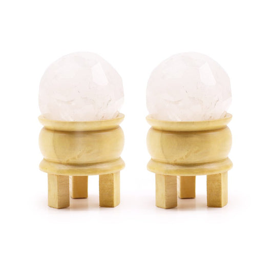 Two faceted quartz spheres rest on small, light-colored wooden stands with four legs. The stands and spheres are positioned on a white background.