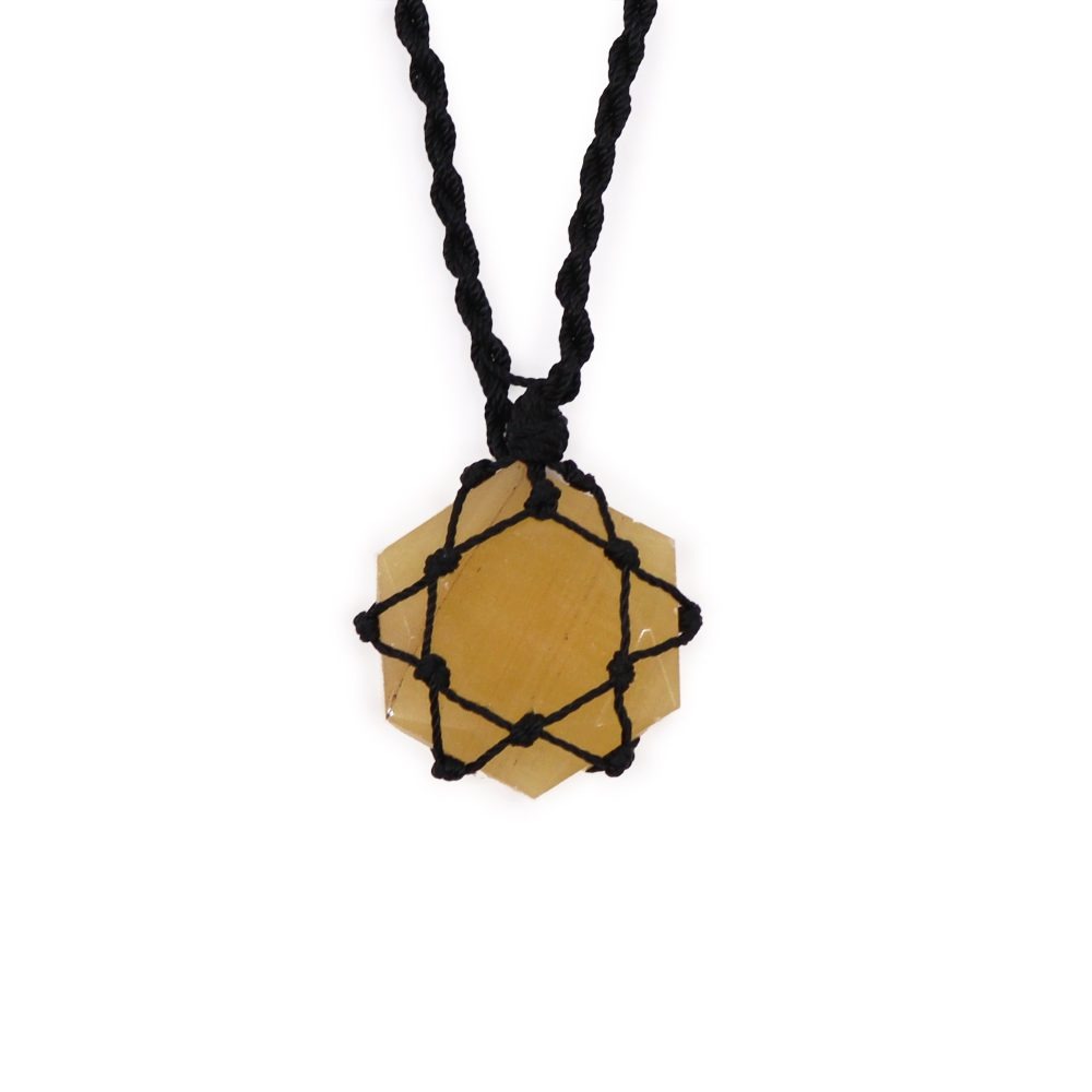A hexagonal, yellow stone hangs from a braided black cord. The stone is held in place by a black, star-shaped cord weaving. It is isolated on a white background.