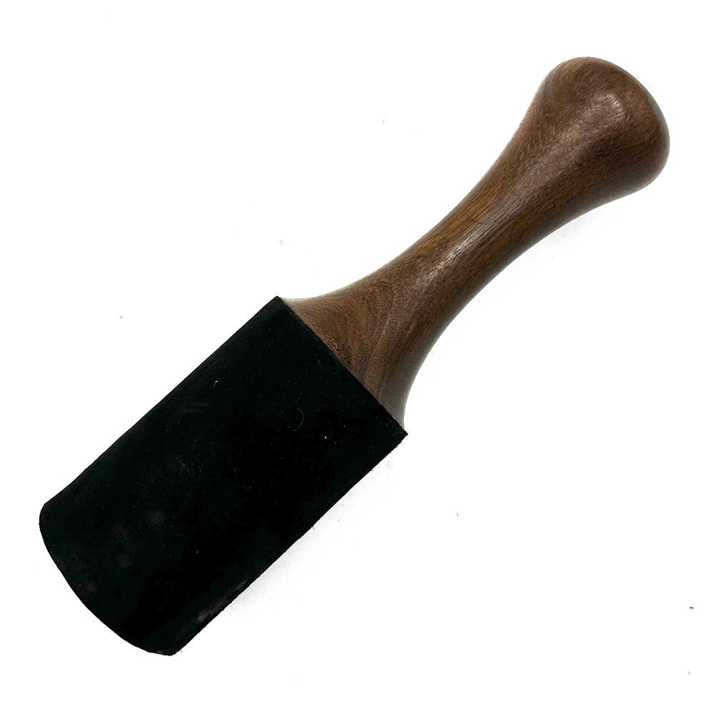 A wooden mallet with a black, padded striking surface rests on a white background.