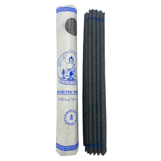 Package of incense sticks next to a cylindrical paper container with a blue Buddha illustration and text: "Medicine Buddha," "Healthy Living," and script in another language.