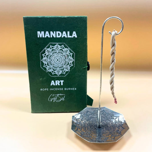 A rope incense burner hangs from a metallic stand with a decorative base. Behind, a green box displays: "MANDALA ART, ROPE INCENSE BURNER, Gift Set," featuring an intricate mandala design.