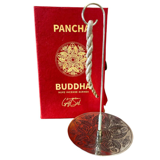 A twisted rope incense hangs on a metallic stand, set against a detailed circular base. Behind it, a red box reads "PANCHA BUDDHA ROPE INCENSE BURNER Gift Set" with intricate designs.