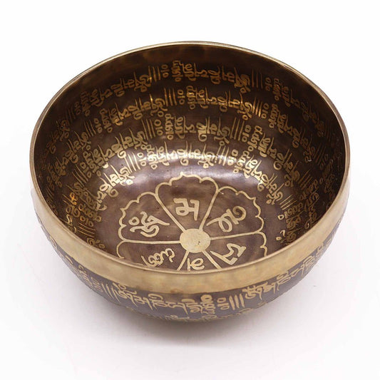 A metallic singing bowl intricately engraved with gold-hued symbols and script lines its interior and exterior, set against a plain white background.