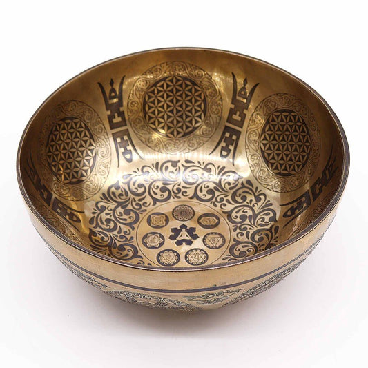 A brass singing bowl features intricate geometric and floral engravings along its interior, set against a white background. The engravings include circular and symmetrical patterns, enhancing its decorative appeal.