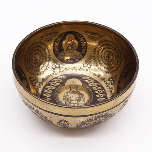 Brass singing bowl, adorned with intricate engravings of seated Buddhas and symbols, features inscribed Tibetan script. The interior showcases a prominent Buddha figure, reflecting Tibetan cultural artistry.