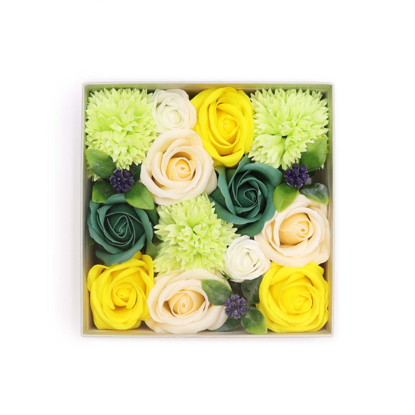 Soap flowers, arranged in a square box, feature yellow, cream, and green roses and carnations. The arrangement is viewed from above, against a white background.