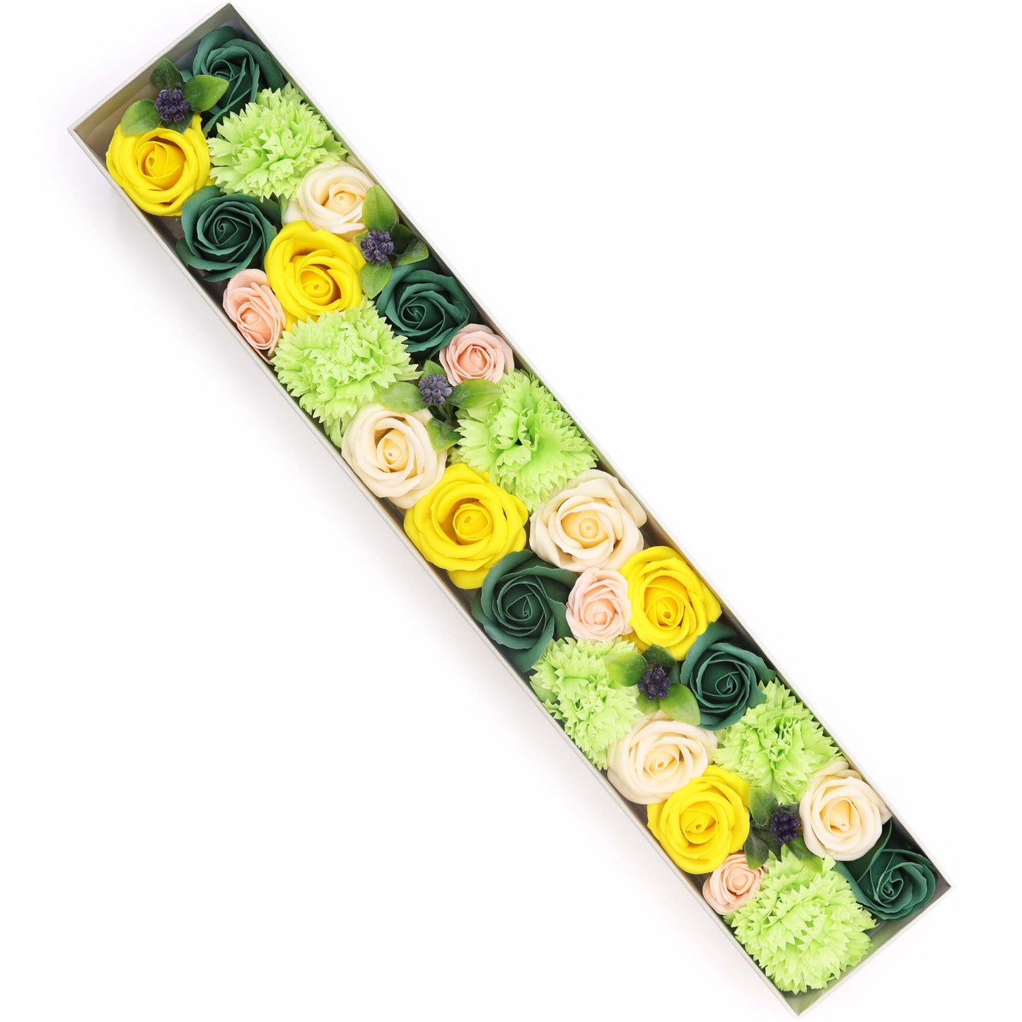 Soap flowers of yellow, green, and cream hues are arranged diagonally in a long, rectangular box against a white background.