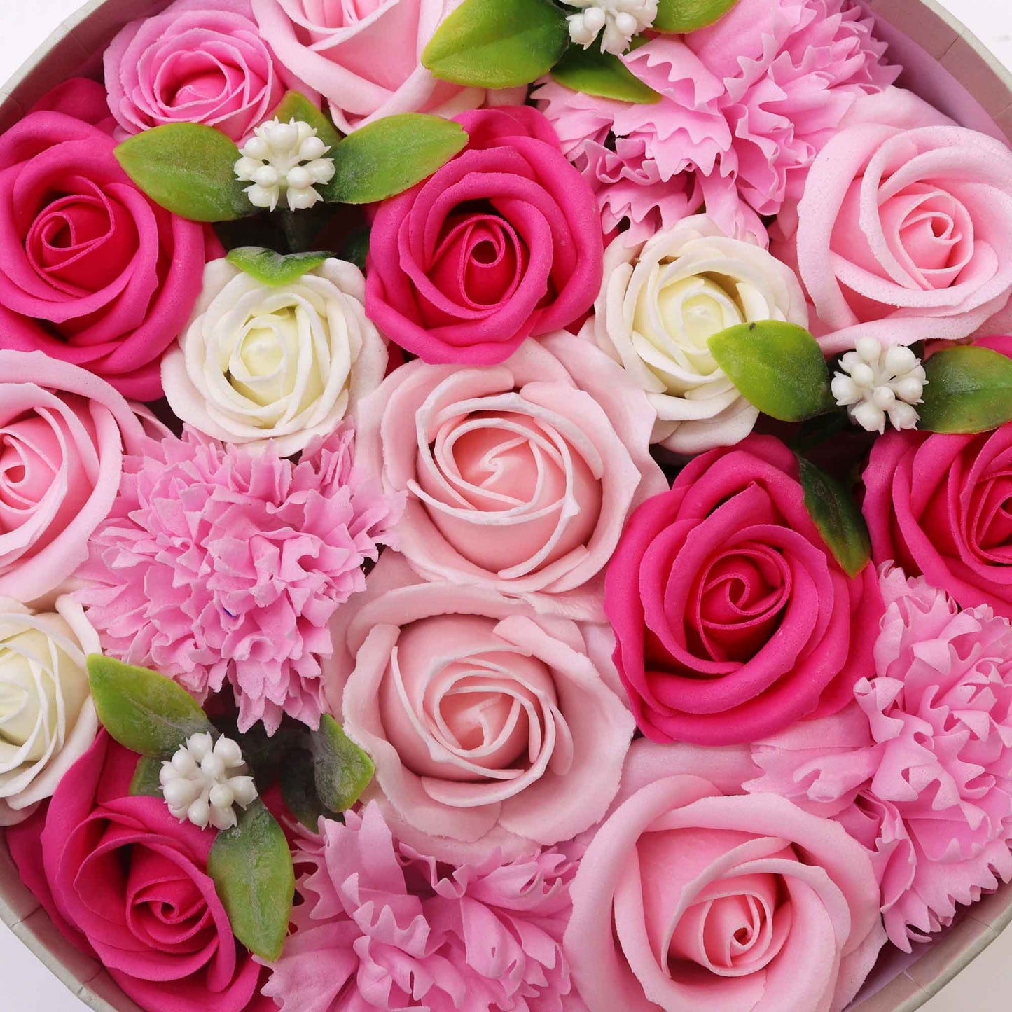 Many pink and white soap roses and carnations are arranged in a circular container.