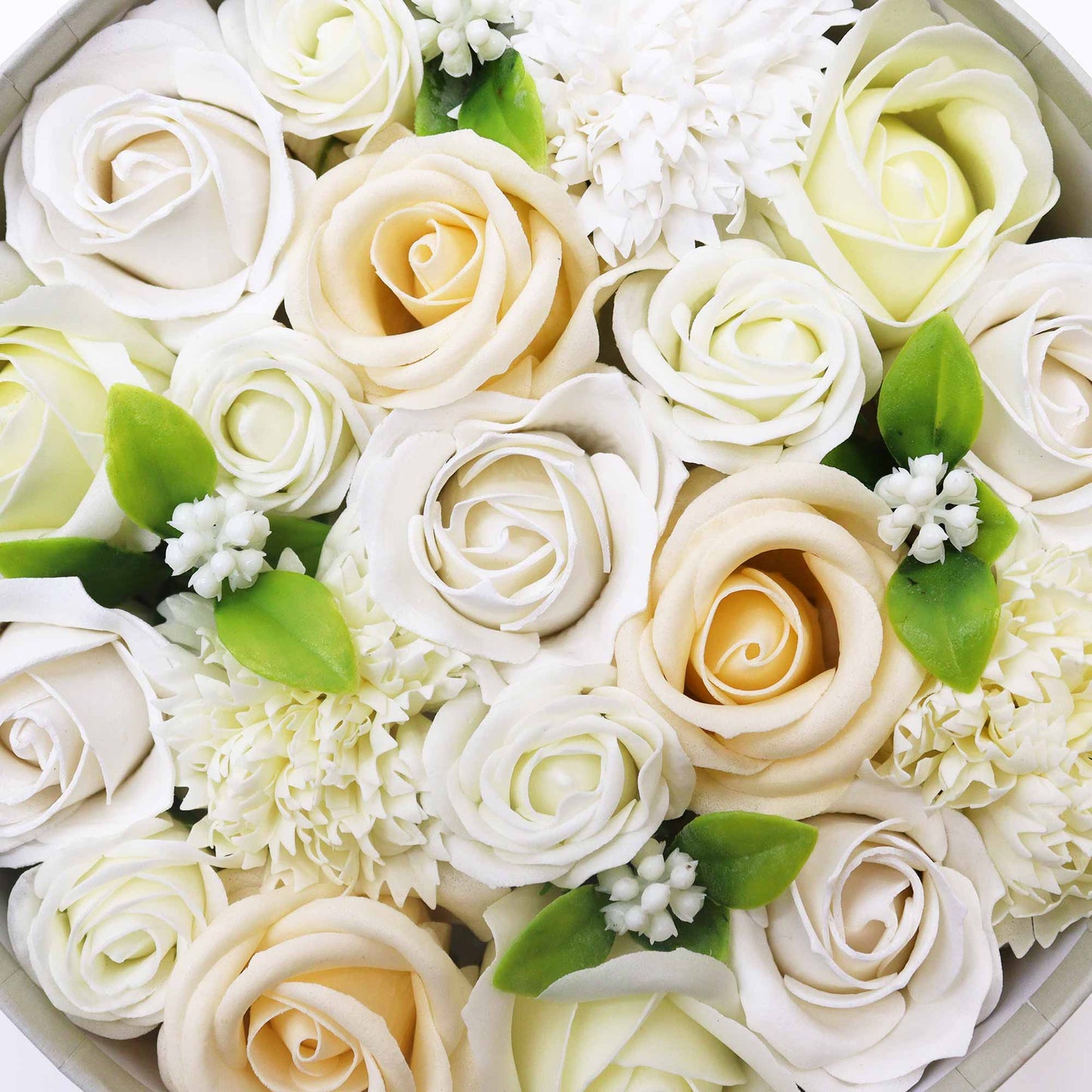 Roses and smaller flowers are arranged in a circular box. The roses are primarily white and cream-colored. The arrangement is tightly packed, creating a full bouquet.