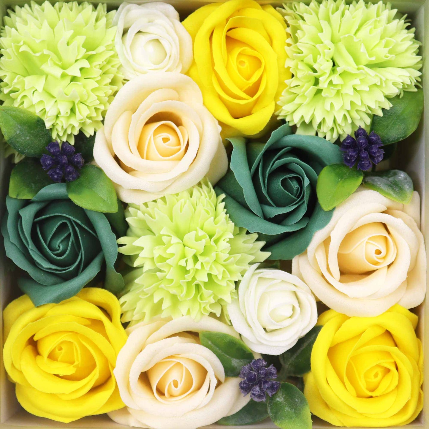Soap roses and carnations are arranged in a box. Yellow, cream, and dark green soap flowers are densely clustered with light green accents.
