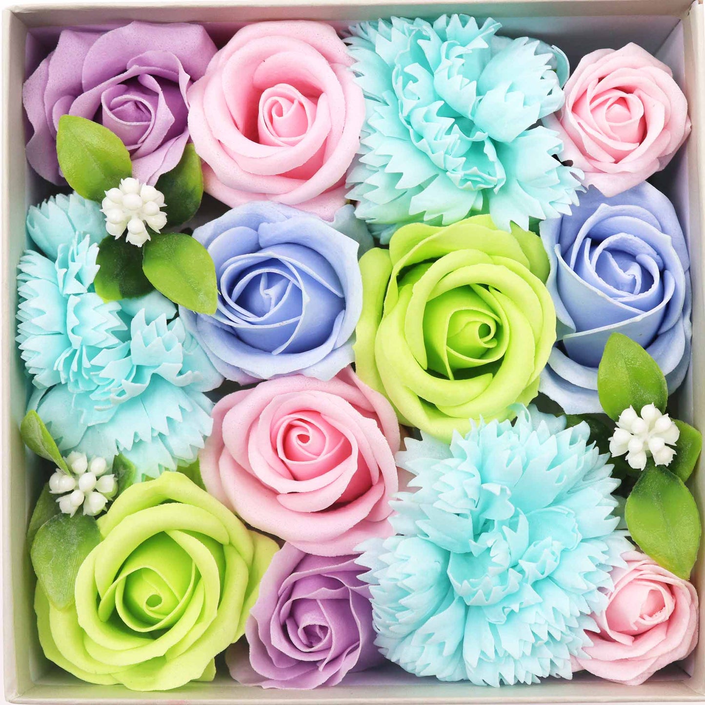 Pastel-colored soap roses and carnations are arranged in a square box. Small white flowers and green leaves are interspersed.