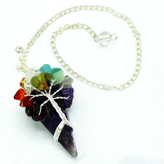 A pendulum on a silver chain is shown on a white surface. The pendulum has an amethyst point, colorful stones, and a silver wire-wrapped tree.