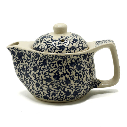 A ceramic teapot, adorned with a navy floral pattern, sits on a white background. It has a lid and a curved handle.