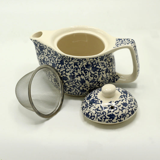 A blue and white patterned teapot sits on a white surface, accompanied by its lid and a separate metal tea infuser.