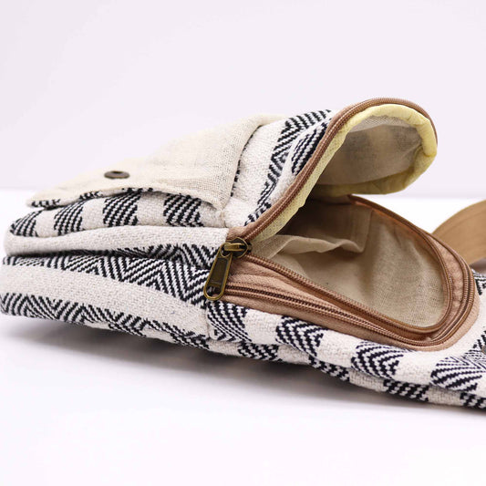 The bag, patterned with black and cream chevrons, sits on a white surface with an open zipper revealing a tan interior.