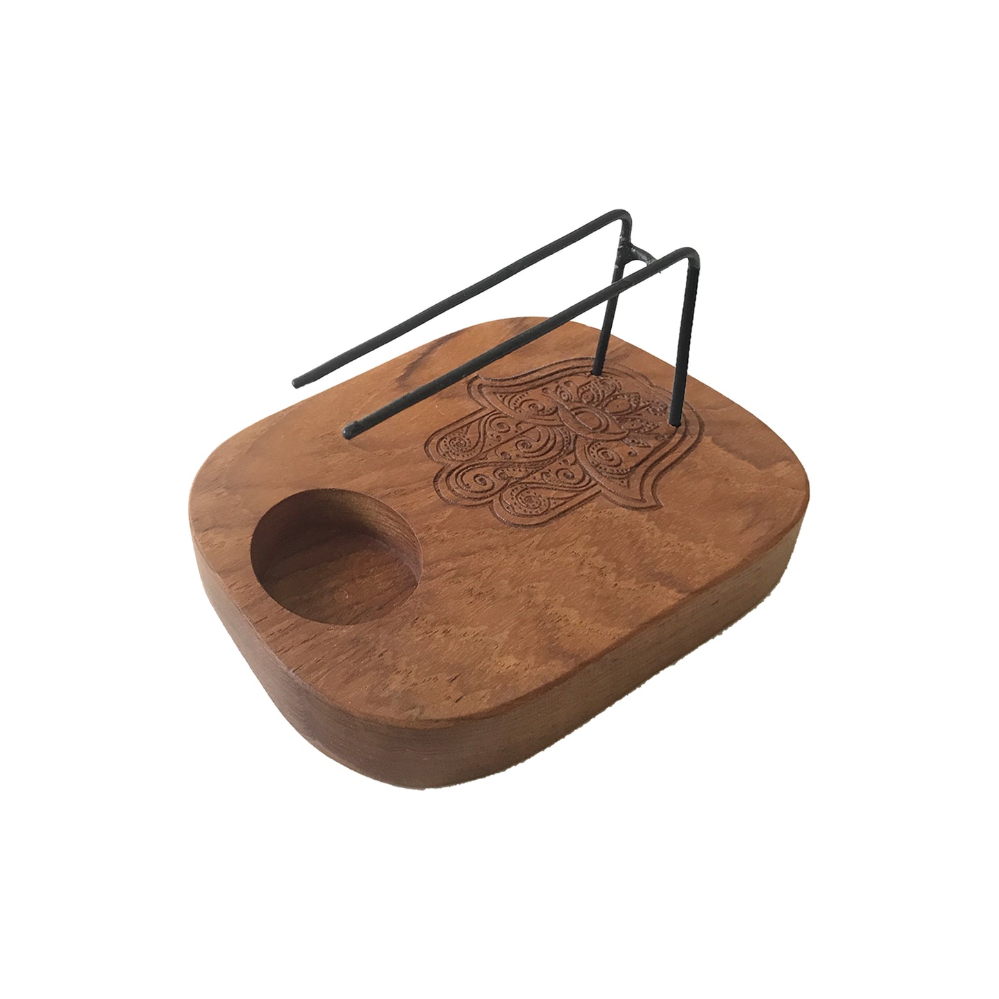 A wooden incense holder, featuring a carved Hamsa hand, holds incense sticks on a small, dark metal stand. It sits on a white background.