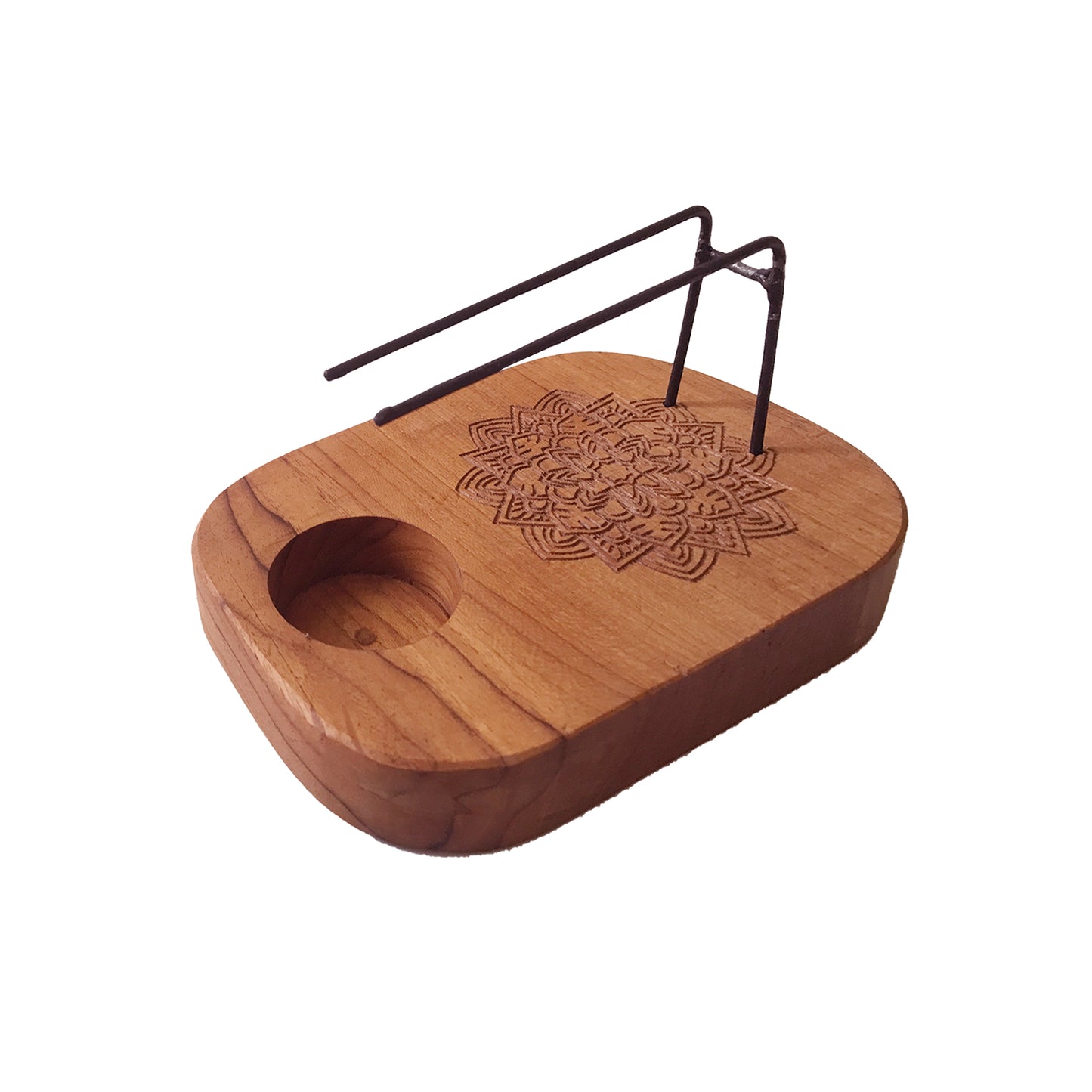 A wooden incense holder rests on a surface. A small, carved mandala is featured on its top. A wire incense burner is affixed to the wood.