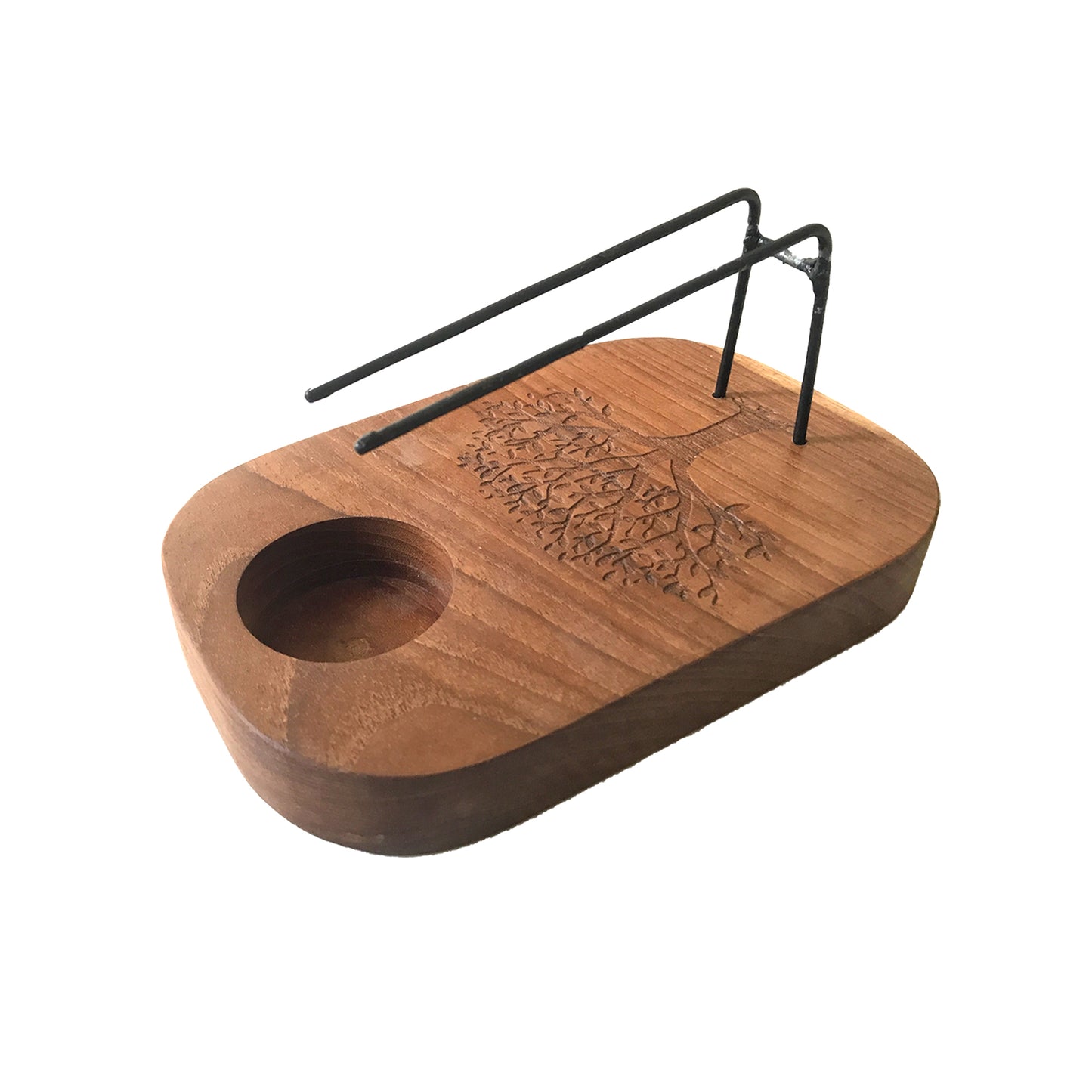 A wooden incense holder with a small candle recess sits on a white background. A simple wire rack holds incense sticks above the base. A tree of life is engraved into the wood.