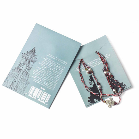 A beaded bracelet rests inside an opened light blue card. The card is printed with the texts "Wear this bracelet to help keep things in perspective..." and other text, plus a picture of a temple.