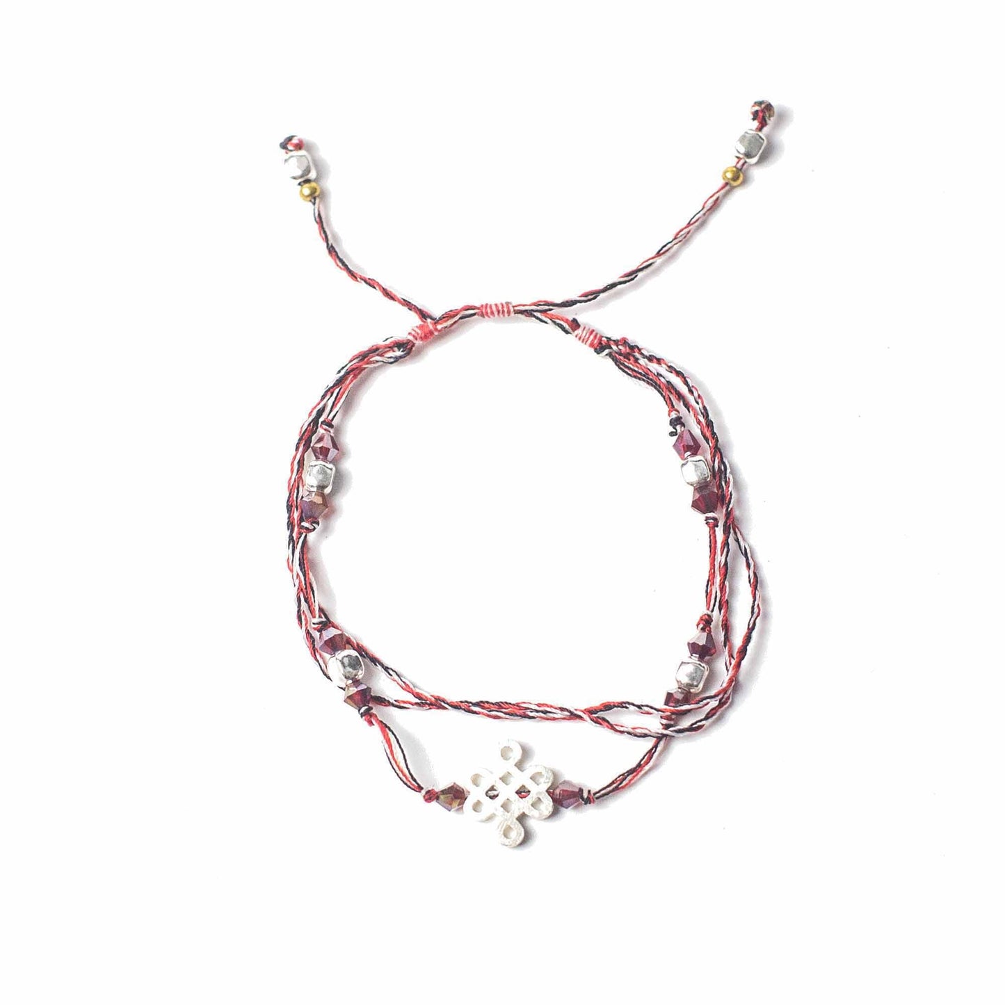 Bracelet made of knotted red, black, and white twine; embellished with silver beads, maroon crystals, and a white knot charm, presented on a white background.