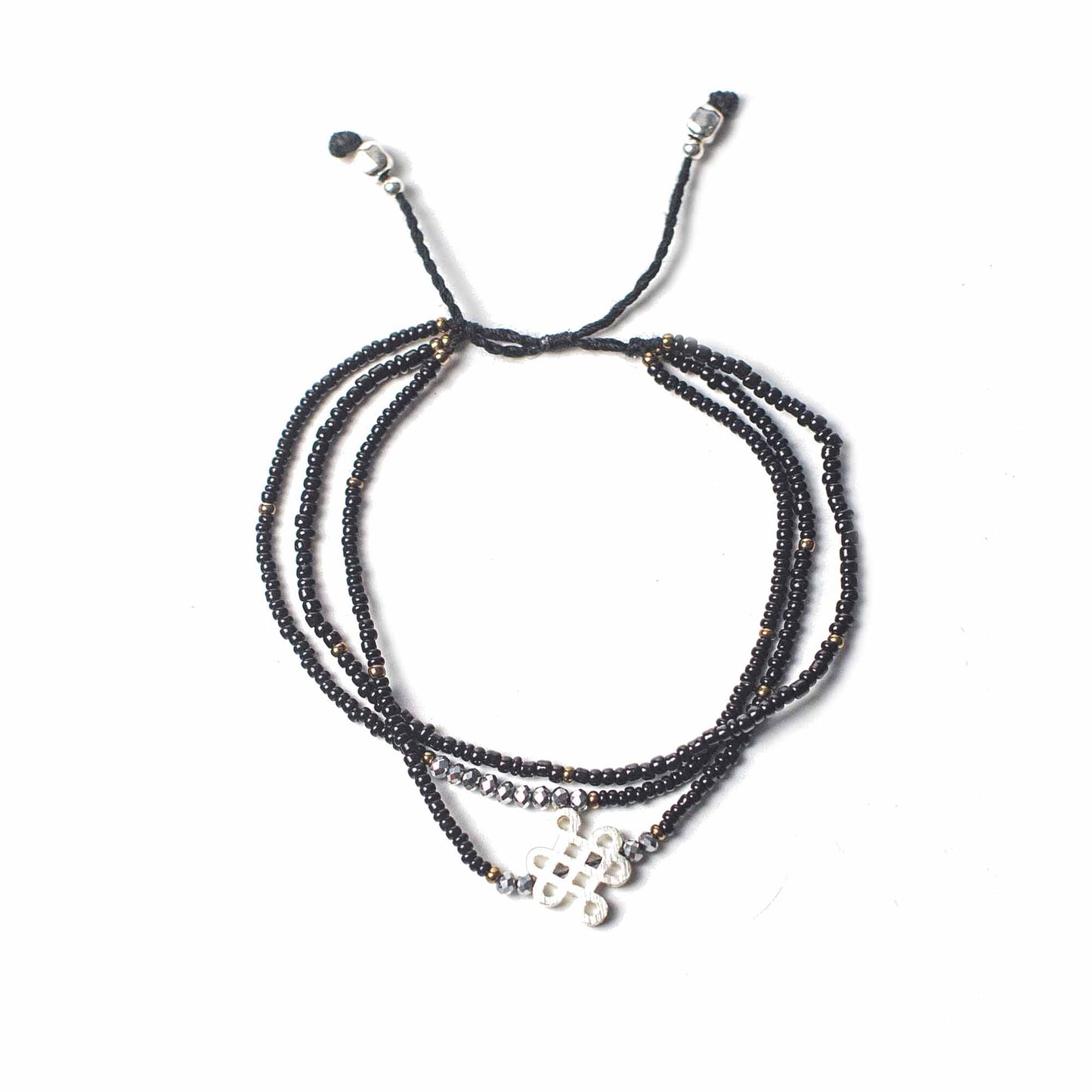 A beaded bracelet displays a knot design on the bottom strand. It’s black with silver accents and is displayed on a white background.
