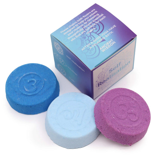 Chakra bath fizzers, in blue and purple, rest beside a box. The box reads: "These chakra bath fizzers are designed to help you unlock your chakra by cleansing your mind. They contain thoughtfully chosen essential oils that are suitable for each chakra. After a good yoga have a relaxing bath. Ancient Wisdom."