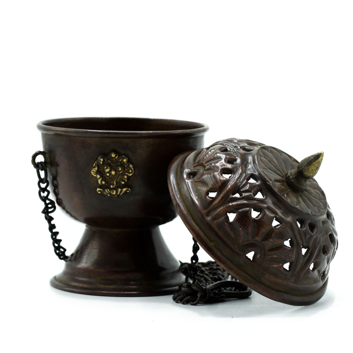Bronze incense holder with a decorative lid resting beside it. The holder features a chain and intricate designs, placed on a plain white background.