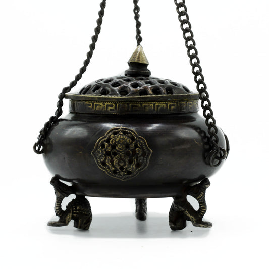 A bronze incense burner stands on three ornate elephant-shaped legs, adorned with intricate carvings, and suspended by three chains, in a minimalist, white background setting.