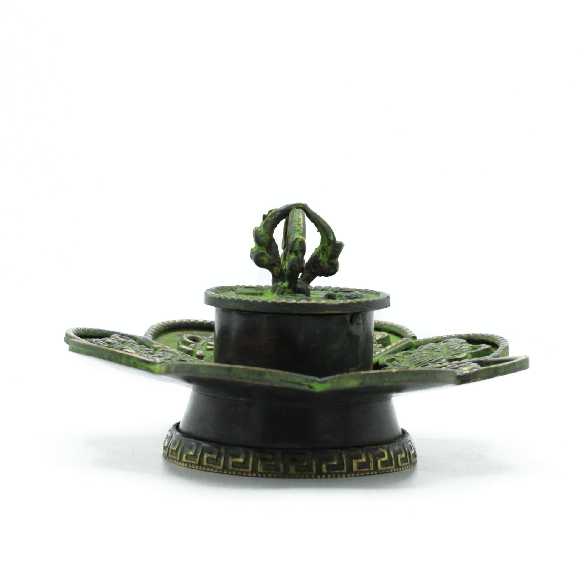 An intricately designed green and bronze inkwell with embossed patterns and a central loop handle, placed on a white surface. The base features a decorative, geometric motif.