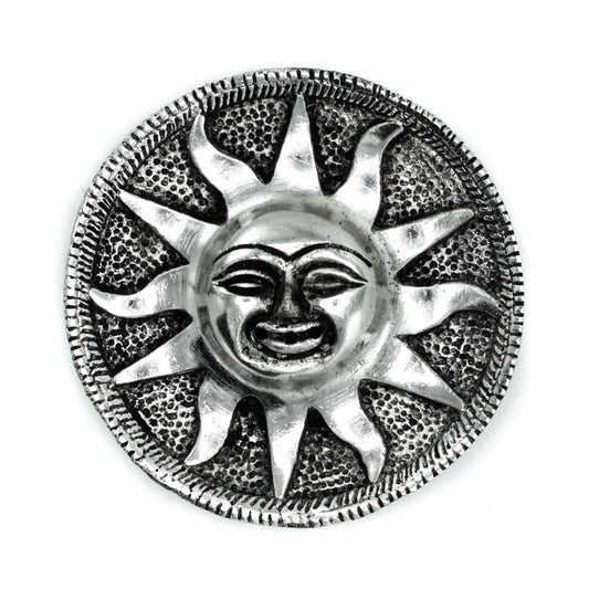 A metallic sun sculpture with a smiling face, featuring prominent rays extending outward, surrounded by a textured circular border, against a plain white background.